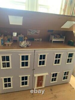 A large vintage dolls house with furniture and dolls