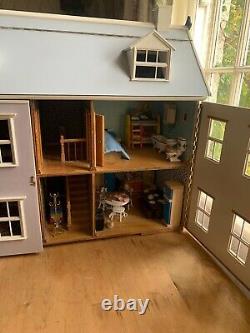 A large vintage dolls house with furniture and dolls